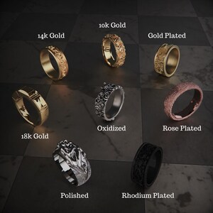 Pu&ograve; includere: Un assortimento di anelli in vari stili e finiture, tra cui 10k Gold, 14k Gold, 18k Gold, Gold Plated, Oxidized, Rose Plated, Polished e Rhodium Plated. Ogni anello presenta design e texture uniche, esposti su una superficie scura a scacchi.
