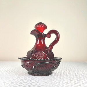 Puede incluir: Una taza de cerámica blanca con un asa negra y el texto "But First, Coffee" en negrita negra. La taza está sobre una superficie blanca. La taza mide aproximadamente 10 cm de alto.