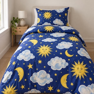 May include: A twin-sized bed featuring a deep blue duvet cover and matching pillowcase decorated with a repeating pattern of yellow suns with faces, yellow crescent moons with faces, small yellow stars, and fluffy light blue clouds.