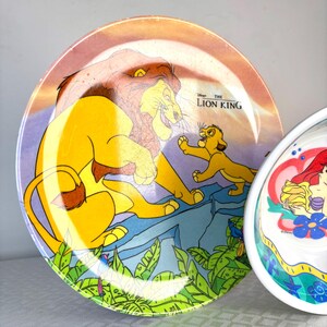Op de afbeelding: Twee decoratieve borden met Disney-personages. E&eacute;n bord toont Simba en Mufasa uit "The Lion King" met de filmtitel. Het andere bord toont Ariel uit "The Little Mermaid". Beide borden hebben kleurrijke ontwerpen.
