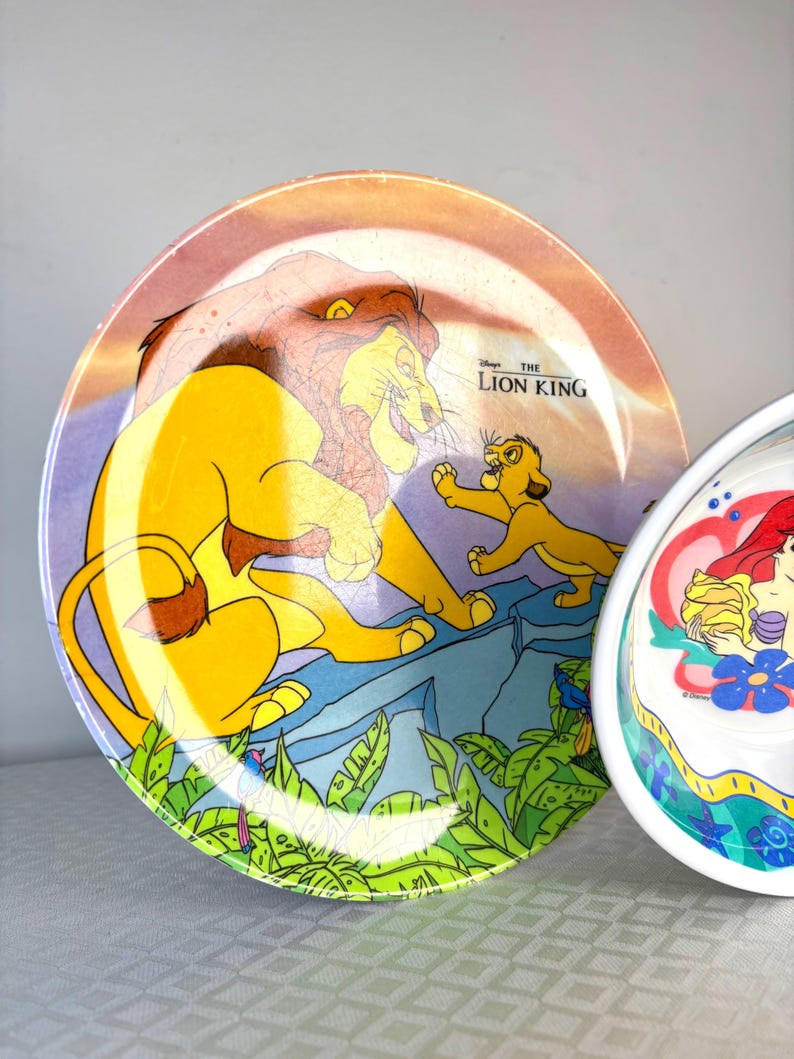 Op de afbeelding: Twee decoratieve borden met Disney-personages. E&eacute;n bord toont Simba en Mufasa uit "The Lion King" met de filmtitel. Het andere bord toont Ariel uit "The Little Mermaid". Beide borden hebben kleurrijke ontwerpen.