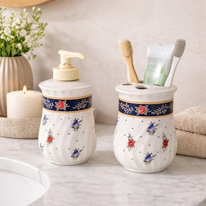 May include: A white ceramic mug with a black handle and the text "But First, Coffee" in a black, handwritten-style font. The mug is on a white surface.
