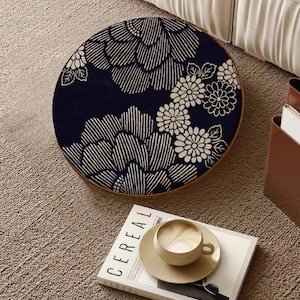 May include: A round, wooden table with a black and white floral design. The table is sitting on a beige carpet.