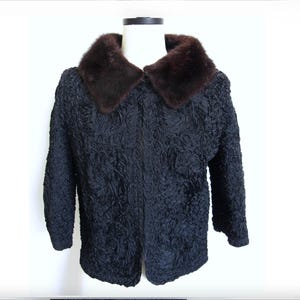 May include: A dark navy blue jacket with a textured pattern. The jacket features a dark brown fur collar. The garment is displayed on a white mannequin against a white background. The jacket has long sleeves.