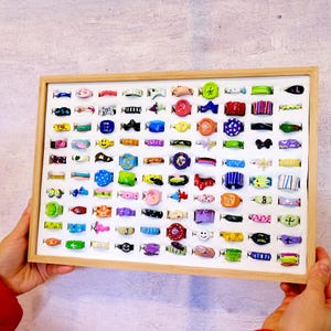 May include: A wooden display case filled with colorful plastic rings. The rings feature various designs, including animals, letters, and geometric shapes.
