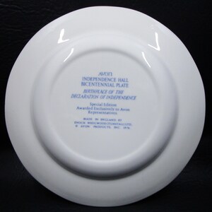 K&ouml;nnte beinhalten: Ein wei&szlig;er Keramikteller mit blauem Text. Der Text lautet "AVON INDEPENDENCE HALL BICENTENNIAL PLATE BIRTHPLACE OF THE DECLARATION OF INDEPENDENCE." Es ist eine Sonderausgabe, hergestellt in England von Enoch Wedgwood (Tunstall) Ltd.