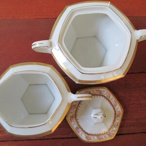 May include: A white porcelain creamer and sugar set with gold trim and a pink floral design on the lid. The creamer and sugar bowl are both octagonal in shape.