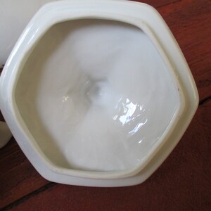 May include: White ceramic lid with a hexagonal shape and a smooth, glossy finish. The lid is designed to fit a matching container.