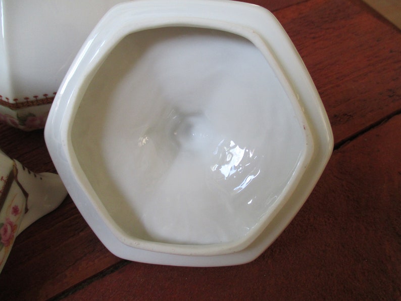 May include: White ceramic lid with a hexagonal shape and a smooth, glossy finish. The lid is designed to fit a matching container.