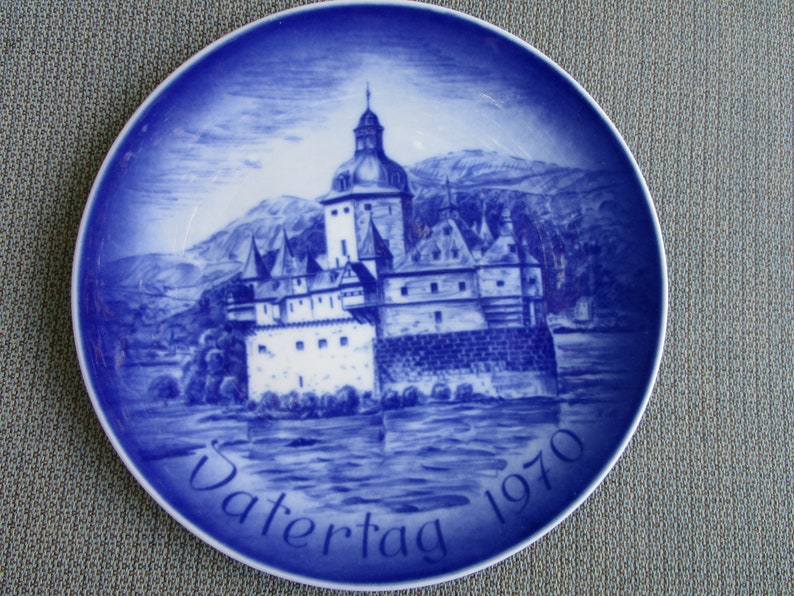 May include: A blue and white porcelain plate with a depiction of a castle and the text "Vatertag 1970".