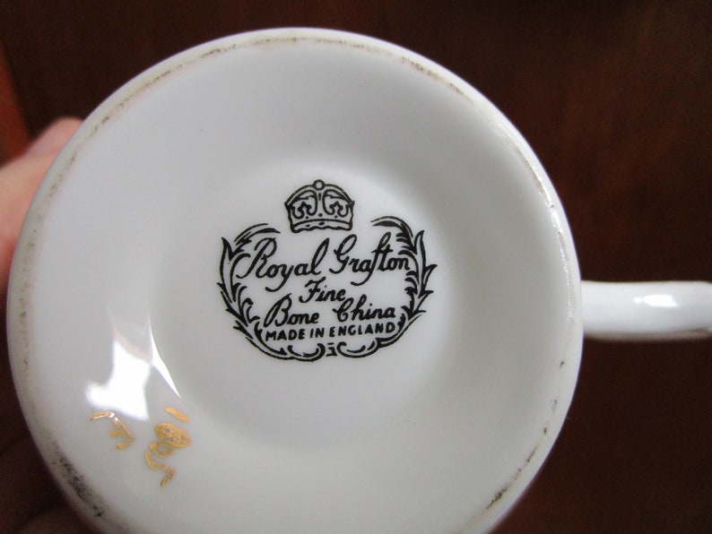 May include: Close-up of the bottom of a white teacup with a black and white Royal Grafton Bone Fine China stamp and a gold number 188.