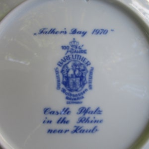 May include: A white ceramic plate with blue text and a blue logo. The text reads "Father's Day 1970", "100 Jahre Bareuther Porzellan", "Walboassen Bavaria Germany", "Castle Pfalz in the Rhine near Kaub".