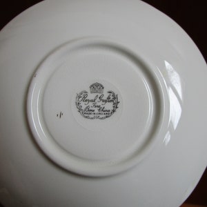 May include: White saucer with a black and white Royal Grafton Bone China stamp. The stamp includes a crown and the words "Made in England".
