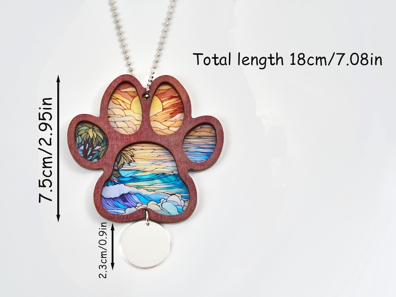 May include: A wooden paw print pendant with a beach scene design. The pendant is 2.95 inches wide and 7.08 inches long, including the chain. The paw print has a sunset and ocean design. A small, round, blank tag hangs below the paw print.