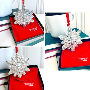May include: A silver snowflake ornament with a red ribbon and a red velvet box with the text "TOWLE Sterling" on the front.