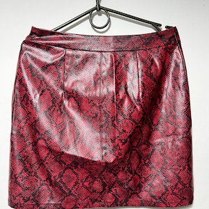 Könnte beinhalten: Ein roter Kunstlederrock mit Schlangenmuster.