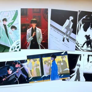 Puede incluir: Una colección de siete láminas artísticas rectangulares con ilustraciones de estilo anime. Las impresiones muestran varios personajes en diversos entornos, incluyendo una habitación roja, un tren y ambientes abstractos oscuros, con paletas de colores que van desde azules y rojos vibrantes hasta blanco y negro monocromático.