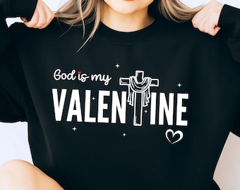 May include: Black sweatshirt with the text "God is my Valentine" in white, featuring a cross and heart graphic. The design includes small star accents, creating a festive and faith-based theme.