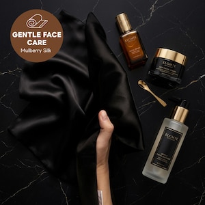 Puede incluir: Un paño de seda de morera negra junto a productos de cuidado facial ELGMTE, incluyendo un sérum, una crema rica, un limpiador suave y una pequeña cuchara dorada. Un gráfico circular marrón muestra el texto GENTLE FACE CARE Mulberry Silk.
