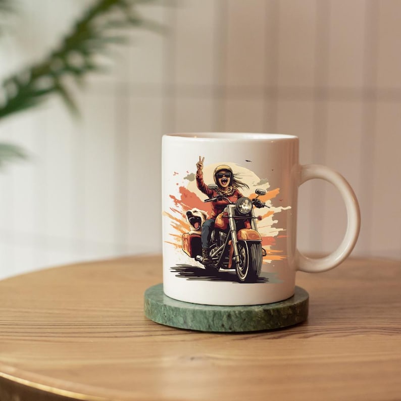 May include: White ceramic mug featuring a vibrant illustration of a person riding a motorcycle, giving a peace sign. The design includes a dog in the sidecar and a sunset-like background. The mug sits on a green marble coaster.