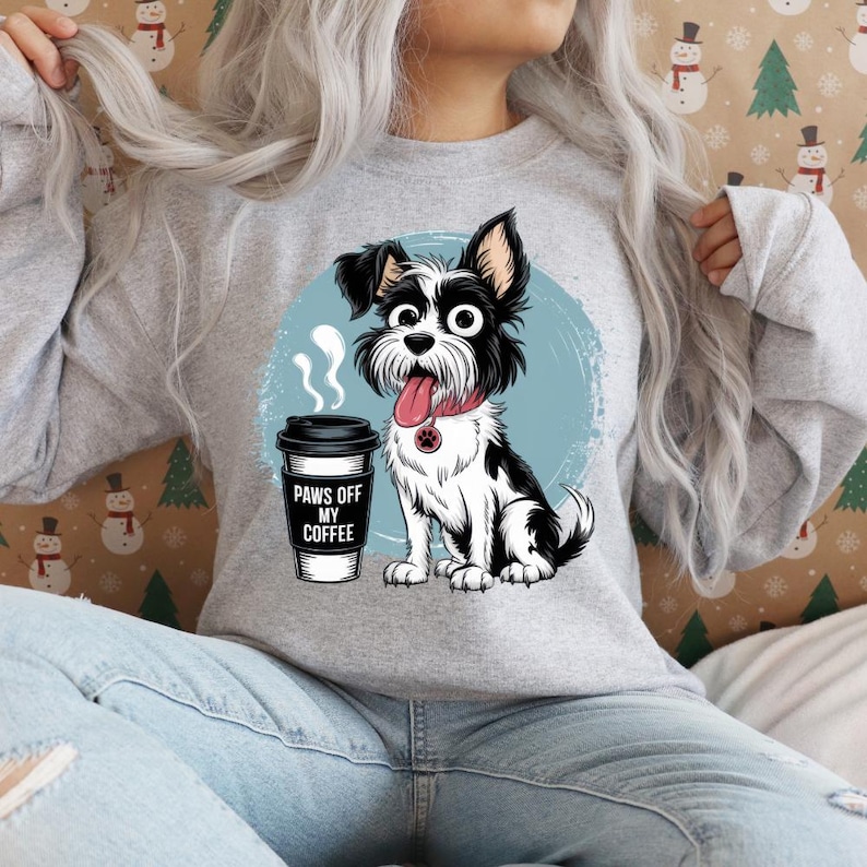 May include: A gray sweatshirt featuring a graphic of a black and white dog with its tongue out, a red collar, and a coffee cup. The coffee cup has the text "Paws Off My Coffee". The dog is set against a blue background.
