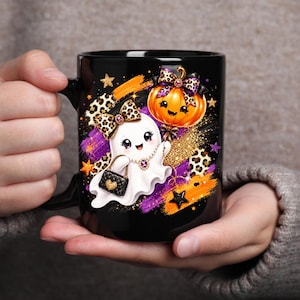 May include: A black ceramic mug featuring a graphic of a white ghost wearing a leopard print bow and carrying a black quilted handbag. The ghost holds an orange pumpkin balloon with a matching leopard print bow, set against purple and gold accents.