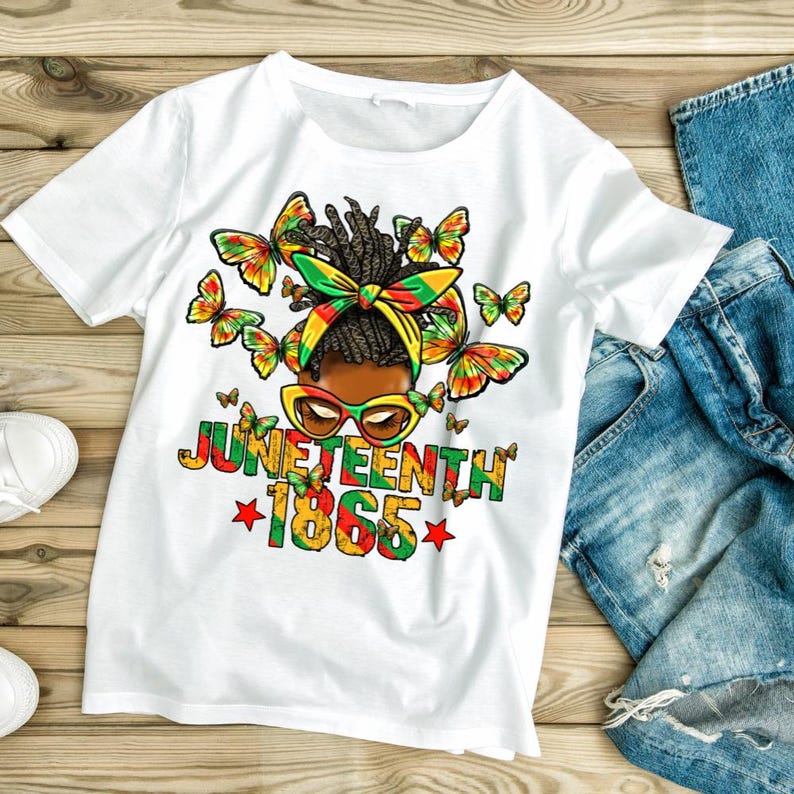 Pu&ograve; includere: T-shirt bianco con grafica colorata che celebra il Juneteenth. Il design presenta il volto di una donna con farfalle, occhiali da sole e un copricapo nei colori panafricani. &Egrave; incluso anche il testo "Juneteenth 1865".