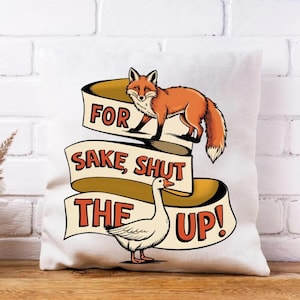 May include: White square pillow with a cartoon fox and goose design. The fox is orange and the goose is white. The pillow has a banner with the text "FOR SAKE, SHUT THE UP!" in orange and black.
