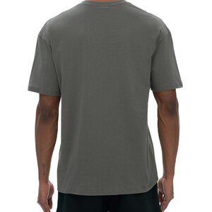 May include: A gray t-shirt with a crew neck and short sleeves. The shirt is made of a soft material and is shown from the back. The model is wearing black shorts. The background is white.