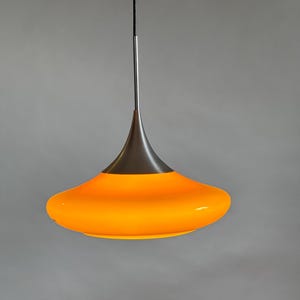 May include: A modern pendant light with a silver metal frame and a bright orange glass shade.