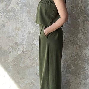 Puede incluir: Un mono sin mangas de color verde oliva con silueta de pierna ancha, cuello redondo y dise&ntilde;o de cuerpo superpuesto. La prenda incluye bolsillos laterales y un acabado liso, ofreciendo una est&eacute;tica sencilla y funcional.