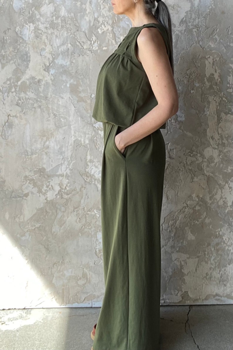 Puede incluir: Un mono sin mangas de color verde oliva con silueta de pierna ancha, cuello redondo y dise&ntilde;o de cuerpo superpuesto. La prenda incluye bolsillos laterales y un acabado liso, ofreciendo una est&eacute;tica sencilla y funcional.