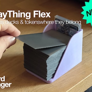 May include: A light purple card holder labeled "The PlayThing Flex" with the text "Keeps decks & tokens where they belong." A hand is shown lifting a card from a stack of cards. The text "NEW! Flex!" is in a green starburst.