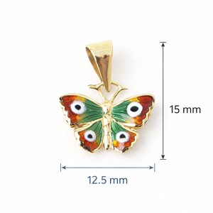 May include: A gold-colored butterfly pendant with green, red, and white enamel detailing. The pendant measures 0.59 inches in height and 0.49 inches in width. The butterfly design features intricate details and a polished finish.