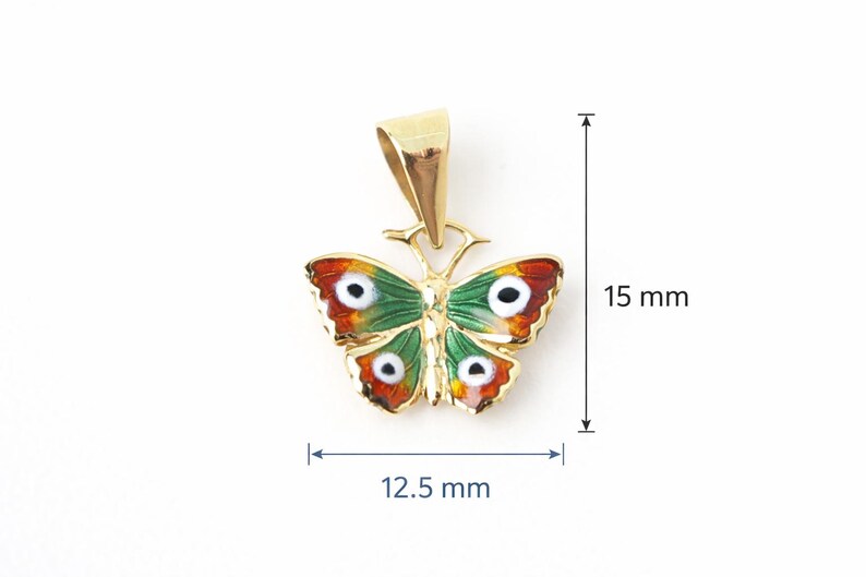 May include: A gold-colored butterfly pendant with green, red, and white enamel detailing. The pendant measures 0.59 inches in height and 0.49 inches in width. The butterfly design features intricate details and a polished finish.
