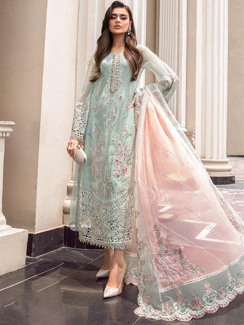 May include: A light blue and pink embroidered dress with a long skirt and long sleeves. The dress has a delicate floral pattern and is made of a sheer fabric.