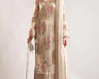 Puede incluir: Un vestido blanco de manga larga de gasa con bordados florales y un dupatta a juego. El vestido tiene un escote redondo y una silueta recta. El dupatta está decorado con un borde plateado.
