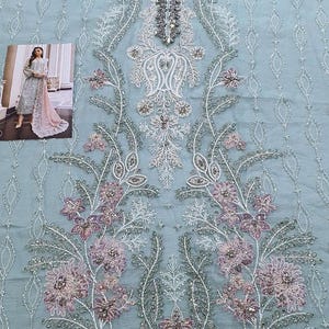 May include: A light blue fabric with intricate white and pink floral embroidery. The fabric is embellished with sequins and beads.