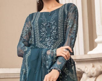 Puede incluir: Un vestido azul teal bordado con una superposición transparente y adornos plateados. El vestido tiene un escote redondo y mangas largas. La tela está etiquetada como "Pure Chiffon".
