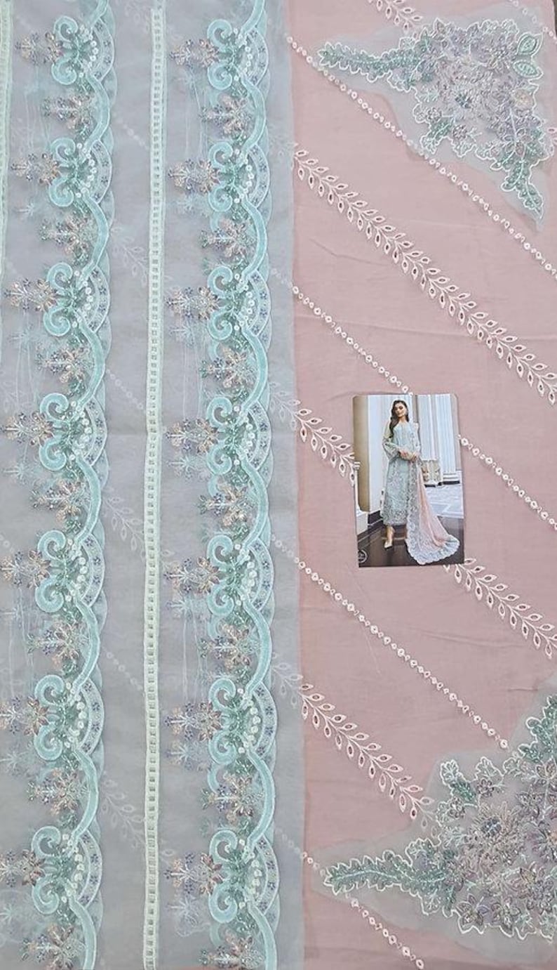 May include: A light blue and pink fabric with intricate floral embroidery. The fabric has a delicate, sheer texture and features a repeating pattern of leaves and flowers.