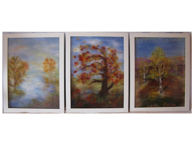 May include: A triptych of framed art pieces depicting autumnal landscapes. Each piece features a white frame and showcases trees with vibrant red, orange, and yellow foliage against a backdrop of blue skies and soft, muted colors. The artwork evokes a sense of tranquility.