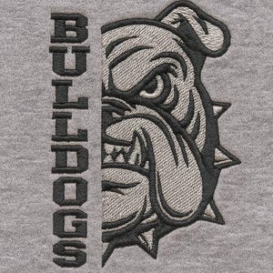 Puede incluir: Diseño bordado de la cara de un bulldog en gris y negro sobre un fondo gris. La palabra "BULLDOGS" está bordada verticalmente en el lado izquierdo de la imagen. El bulldog tiene una expresión severa y un collar con púas.