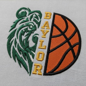 May include: Embroidered design featuring a green bear head on the left and a basketball on the right. The word "BAYLOR" is vertically embroidered in gold. The design is on a light gray fabric.
