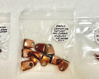 May include: Three small plastic bags containing copper jewelry findings. One bag holds a copper slider, another has straight end cap loops, and the third contains cord crimp tubes with loops. Each bag has a handwritten label with product details.