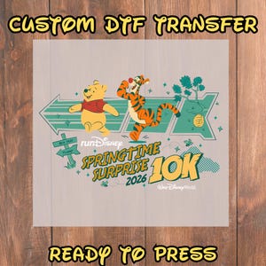 May include: A ready-to-press custom DTF transfer featuring Winnie the Pooh and Tigger from Disney's Springtime Surprise 10K 2026 event. The design includes green arrows, a sign, and the text "READY TO PRESS".