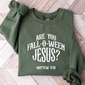 May include: An olive green sweatshirt with the text "ARE YOU FALL-O-WEEN JESUS?" in white, with "MATTHEW 4:19" below. The sweatshirt has a crew neck and long sleeves.