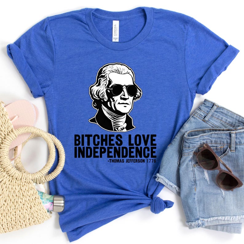May include: A blue t-shirt with a black and white illustration of Thomas Jefferson wearing sunglasses. The text "Bitches Love Independence -Thomas Jefferson 1776" is printed on the shirt.