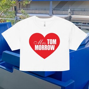 Könnte beinhalten: Weißes Crop-Top mit rotem Herz-Grafik. Das Herz enthält den Text "Mrs. TOM MORROW" in weißer Schrift. Das Shirt besteht aus einem weichen Material.