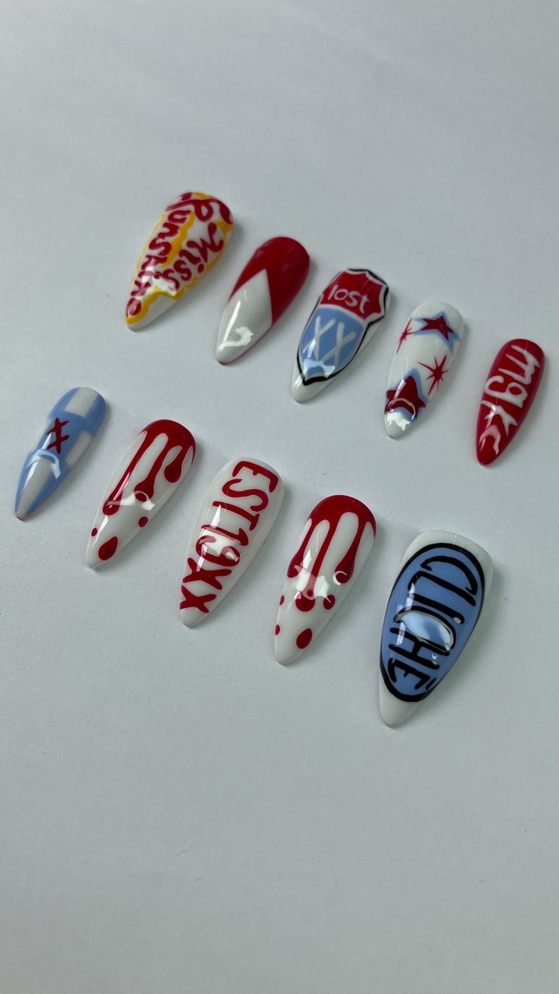 May include: A collection of ten long, almond-shaped artificial nails. Designs include red and white patterns, text, and graphic elements. Some nails feature dripping blood designs, while others display text like "Miss" and "EST19XX".
