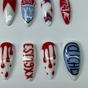 May include: A set of ten long, almond-shaped artificial nails. Designs include red and white geometric patterns, text that reads "lost", "EST 19XX", "mgk", and "cliche", and red blood drop patterns on a white base.